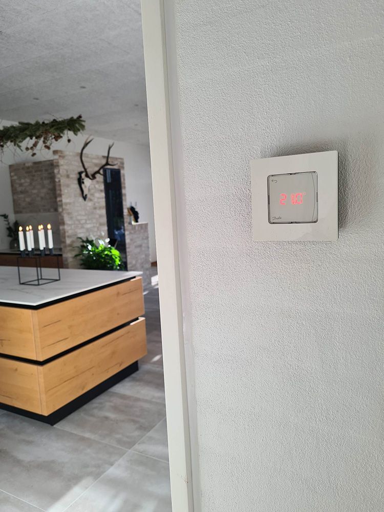 Et køkken med en træø og en termostat på væggen.