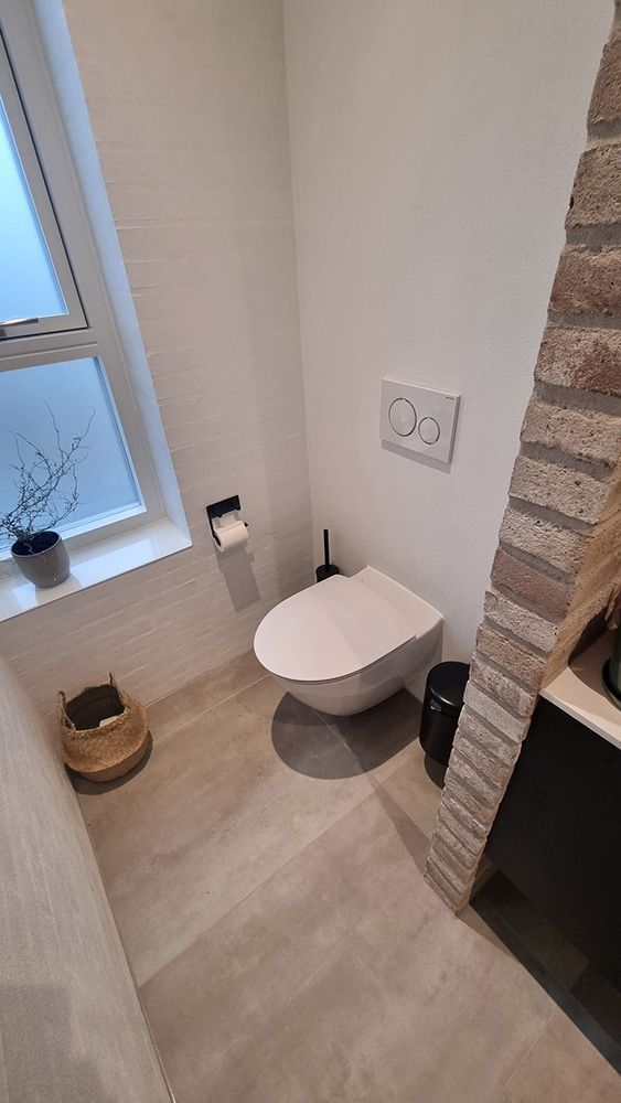 Et badeværelse med toilet, håndvask og vindue.