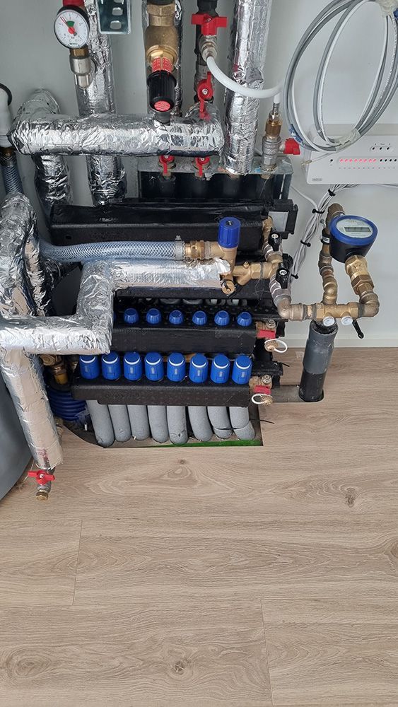 En flok rør sidder under en vask i et køkken.