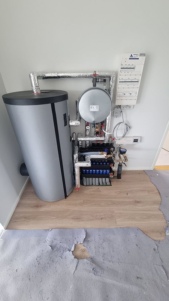 En vandvarmer sidder på et trægulv i et rum.