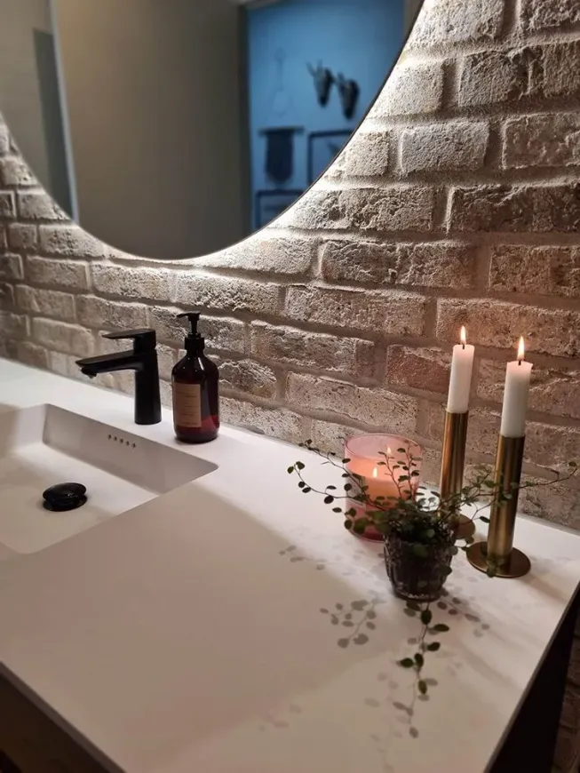 En badeværelsesvask med et spejl og stearinlys på tælleren.