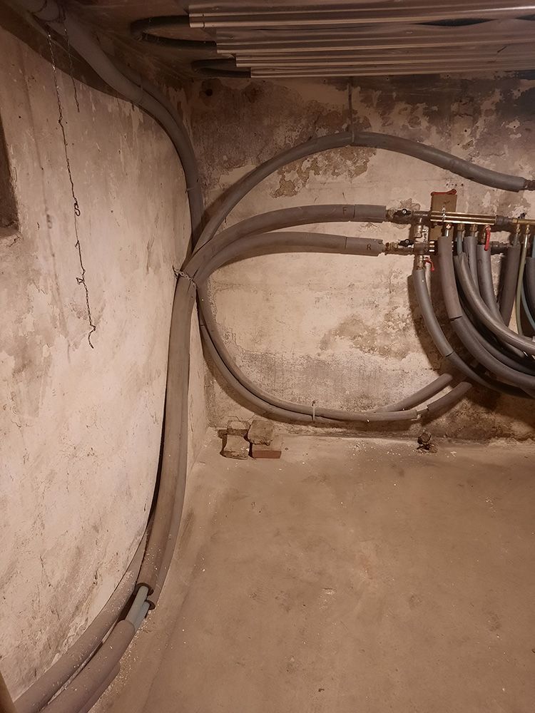 En flok rør er forbundet til en væg i en kælder.