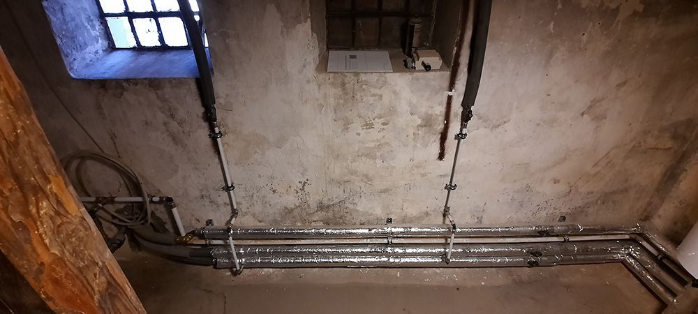 Et rum med en masse rør hængende fra loftet og et vindue.