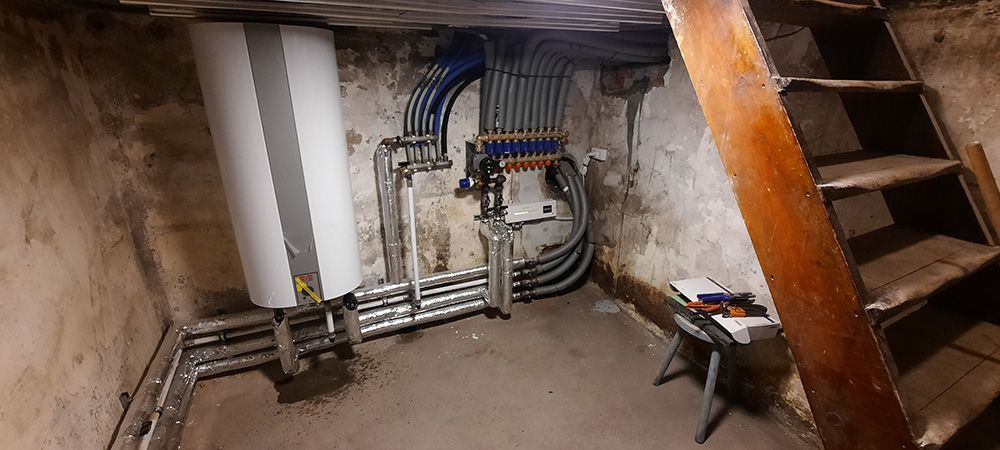 Et værelse med en trappe og en masse rør på væggen.