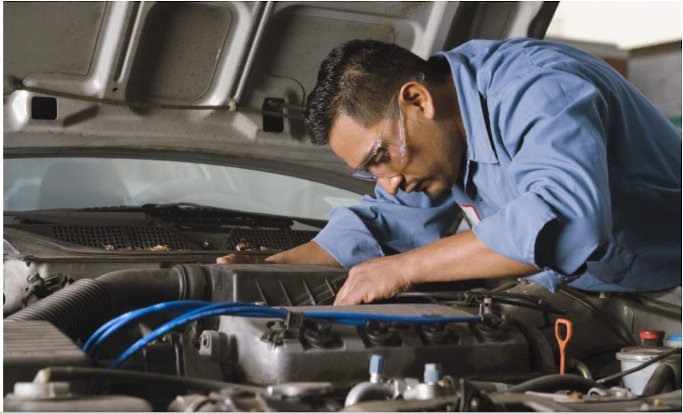 A man in a blue shirt is working on a car engine