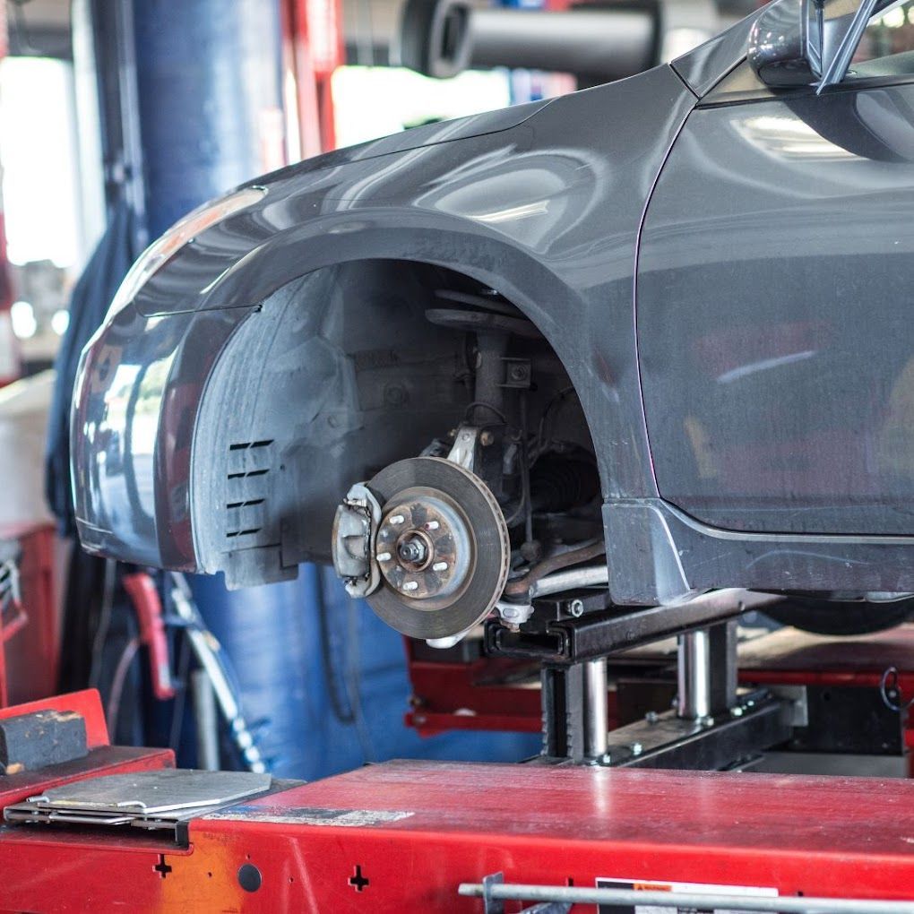 A car is sitting on a lift in a garage.