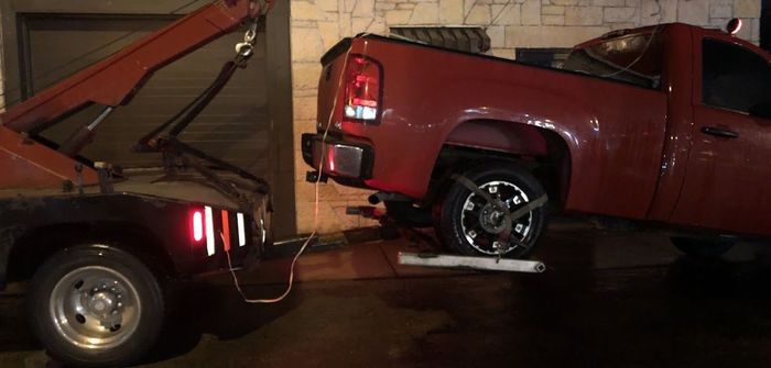 A red truck is being towed by a tow truck.