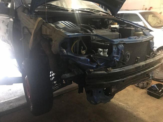 A blue truck with the hood open is sitting in a garage.