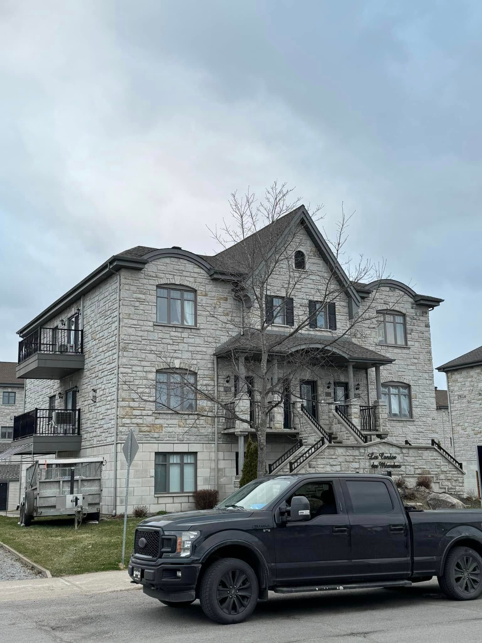 Un camion noir est garé devant un grand bâtiment en pierre.