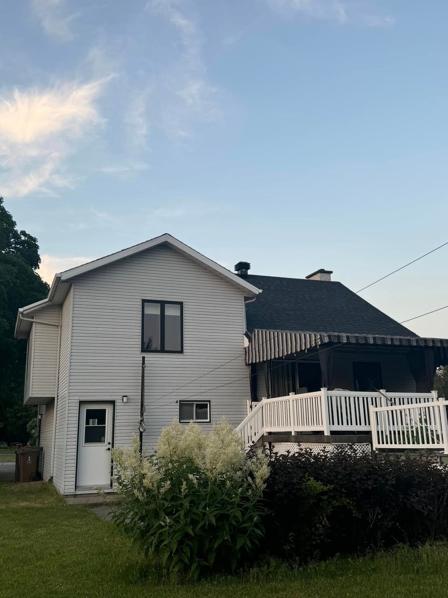 Une maison blanche avec un toit noir et un porche blanc
