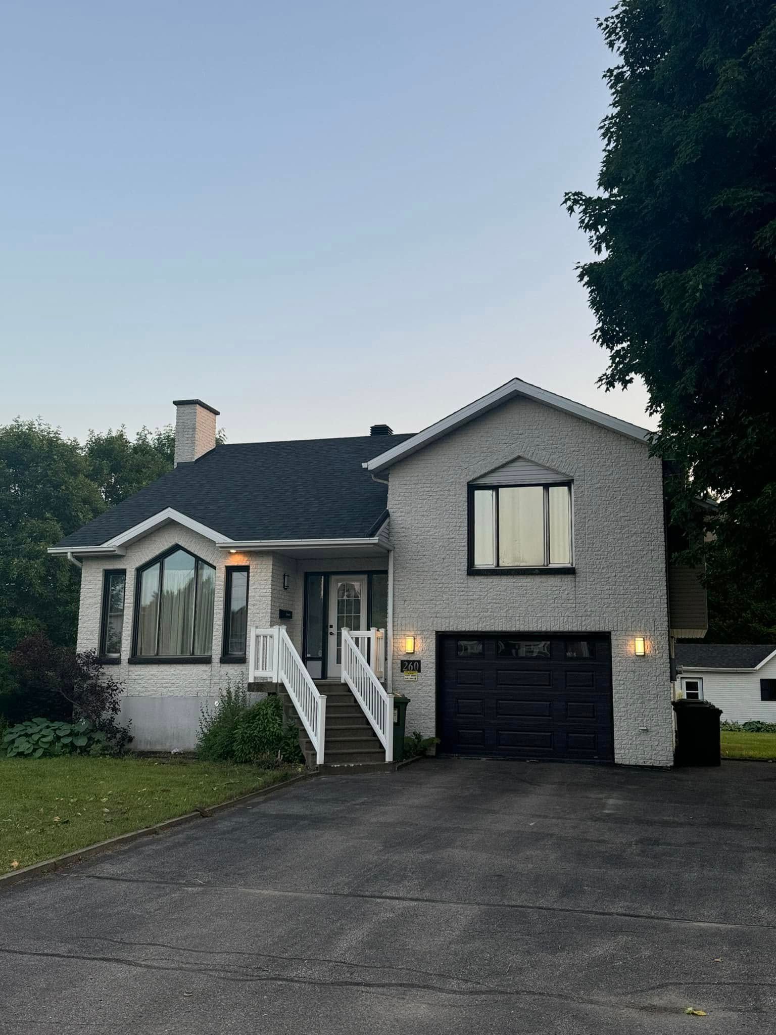 Une maison blanche avec une porte de garage noire et des escaliers
