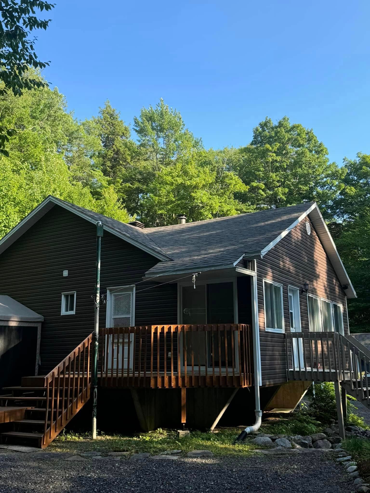 Une maison en bois avec une grande terrasse au milieu d'une forêt.