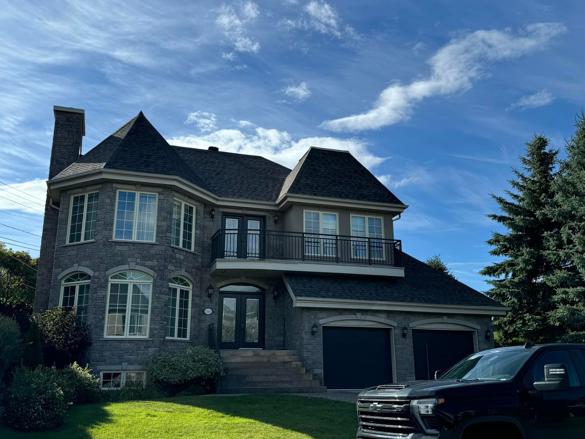 Une grande maison avec un camion noir garé devant.