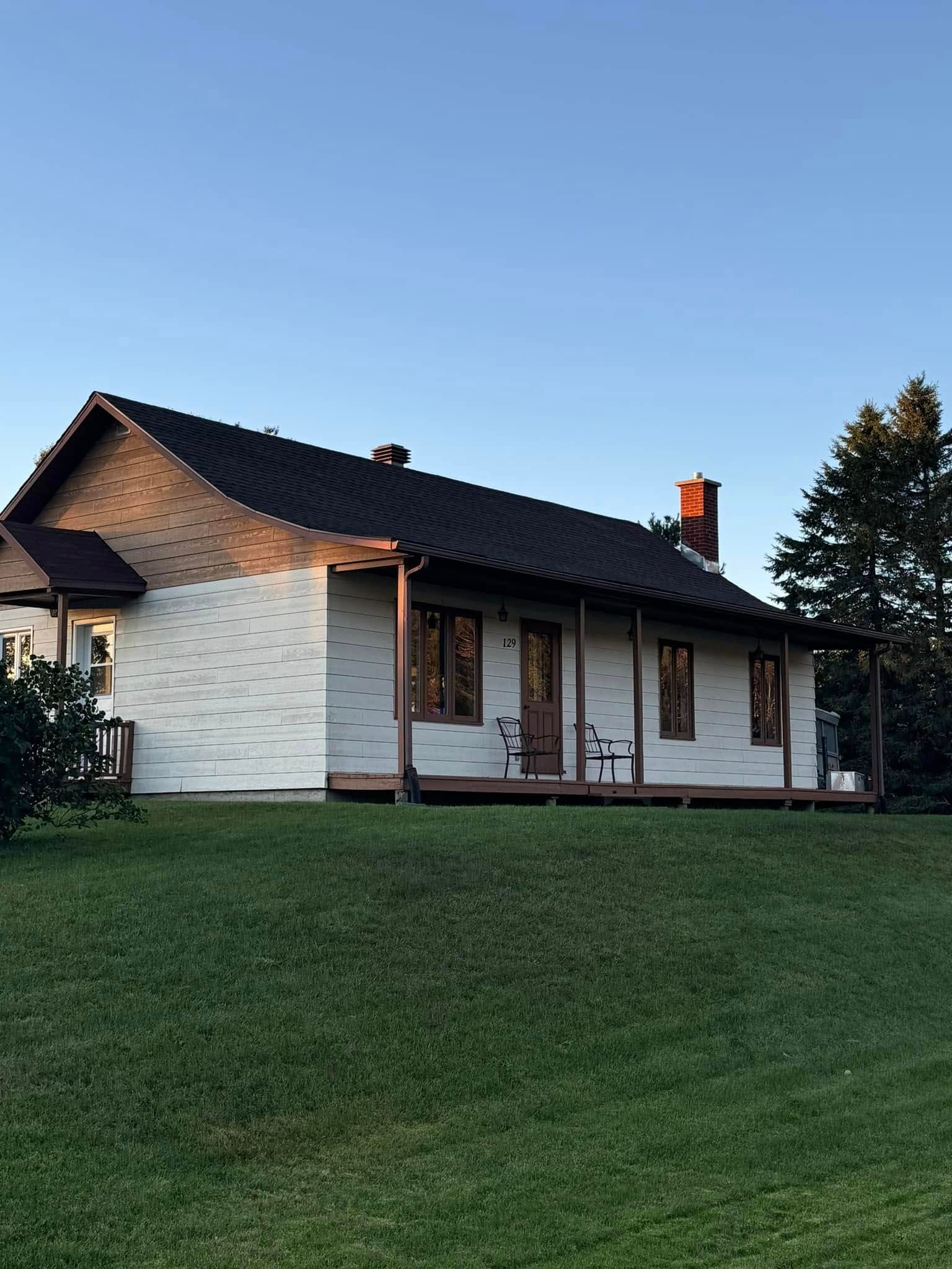 Une maison blanche avec un toit noir et un porche