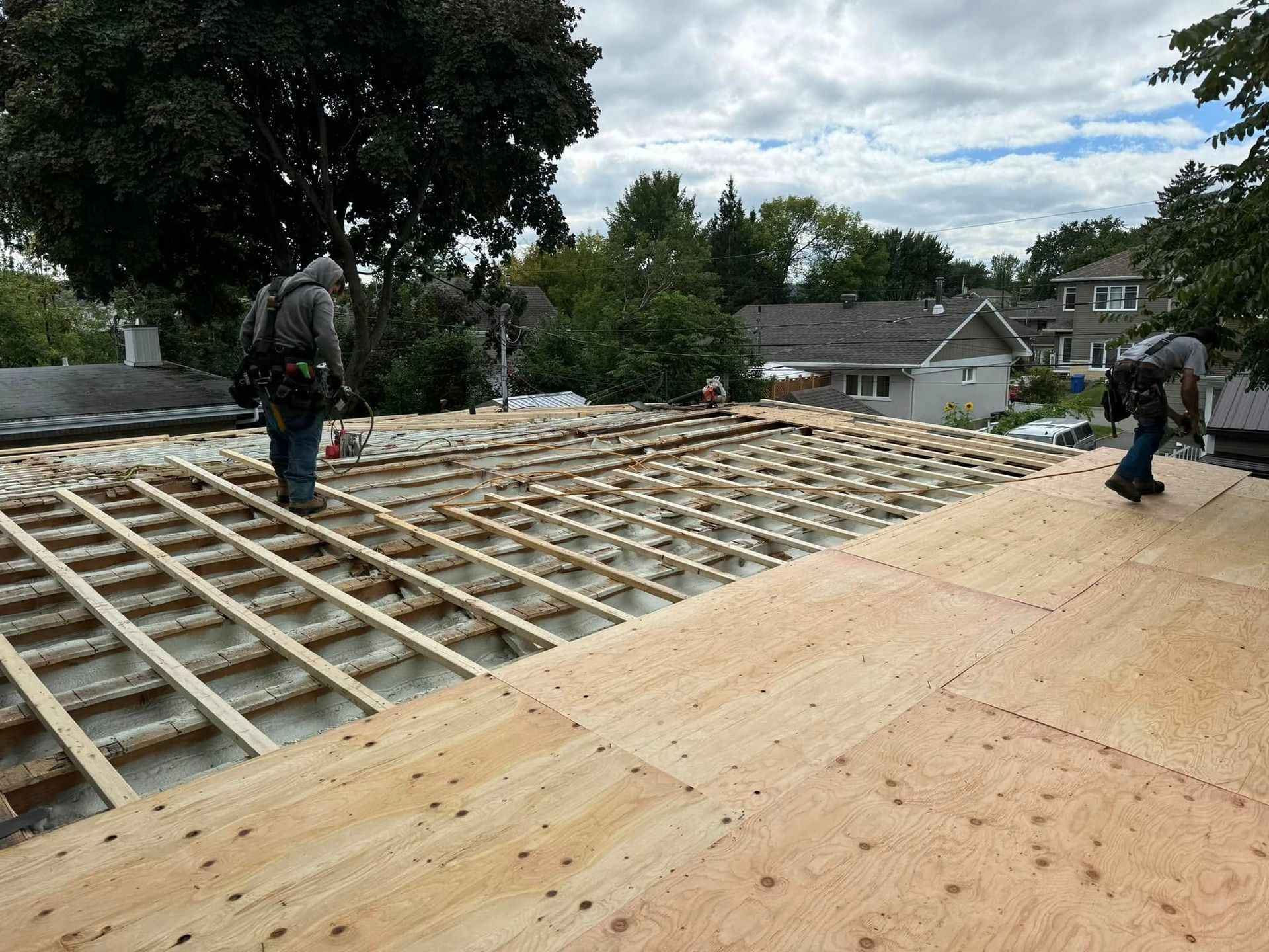 Un groupe d'hommes travaille sur un toit en bois.