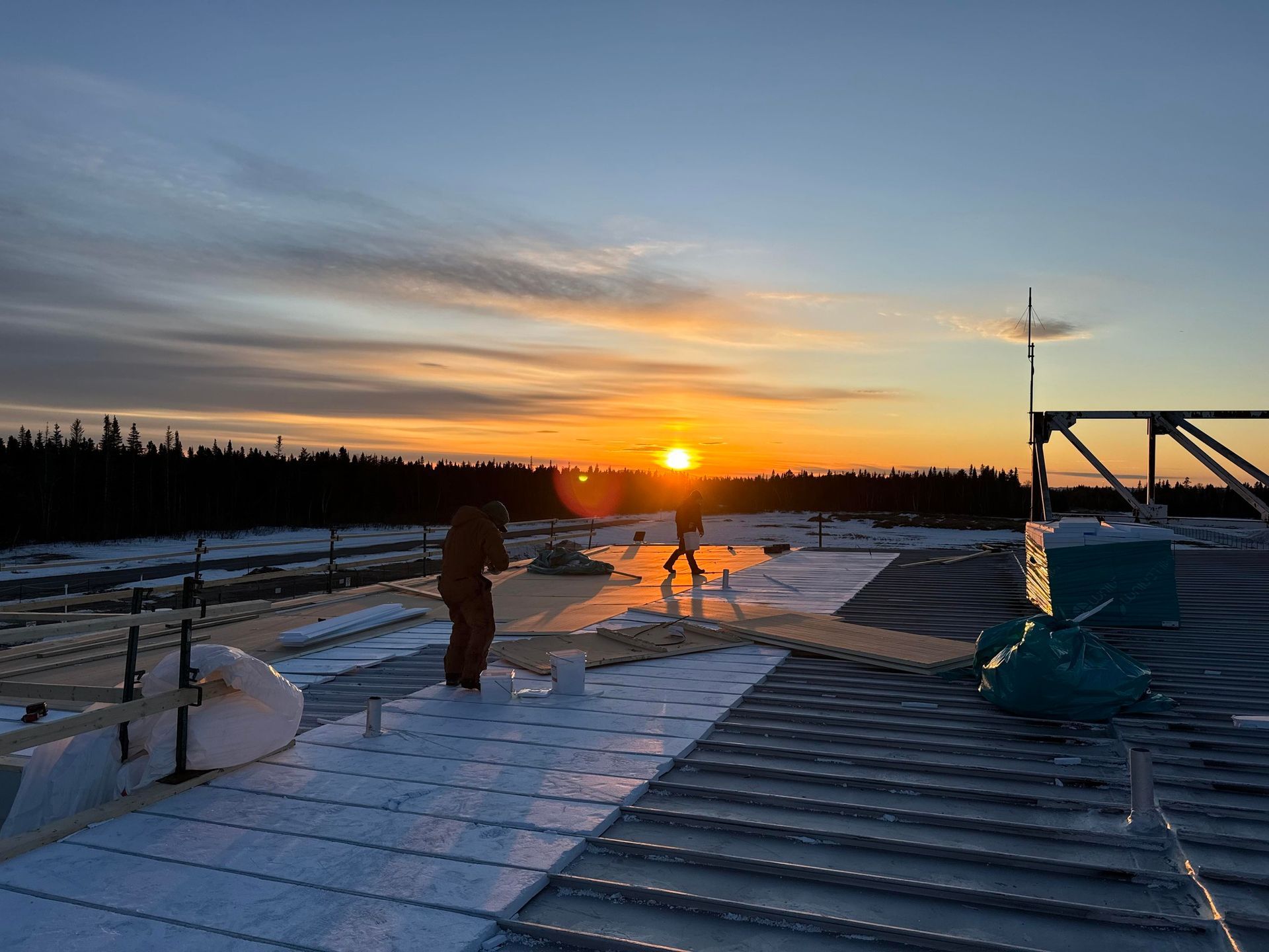 Un homme travaille sur le toit d'un immeuble au coucher du soleil.