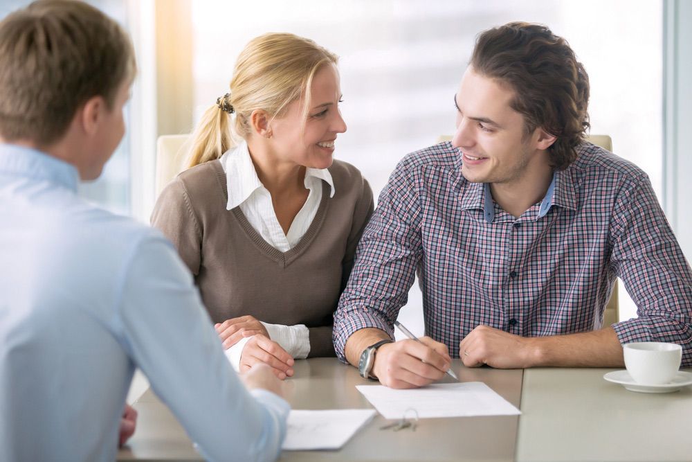 A Man and A Woman Are Sitting at A Table Talking to A Man — A M Conveyancing Pty Ltd In Palm Beach, QLD