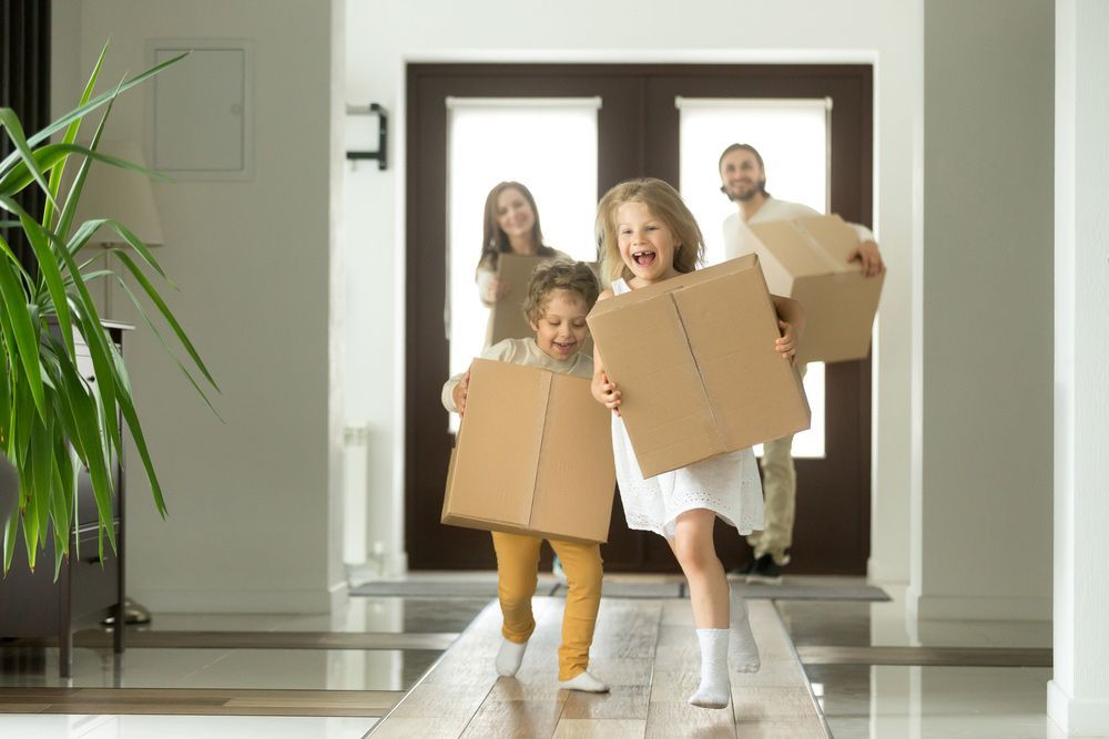 A Family Is Moving Into a New Home and Holding Cardboard Boxes — A M Conveyancing Pty Ltd In Palm Beach, QLD