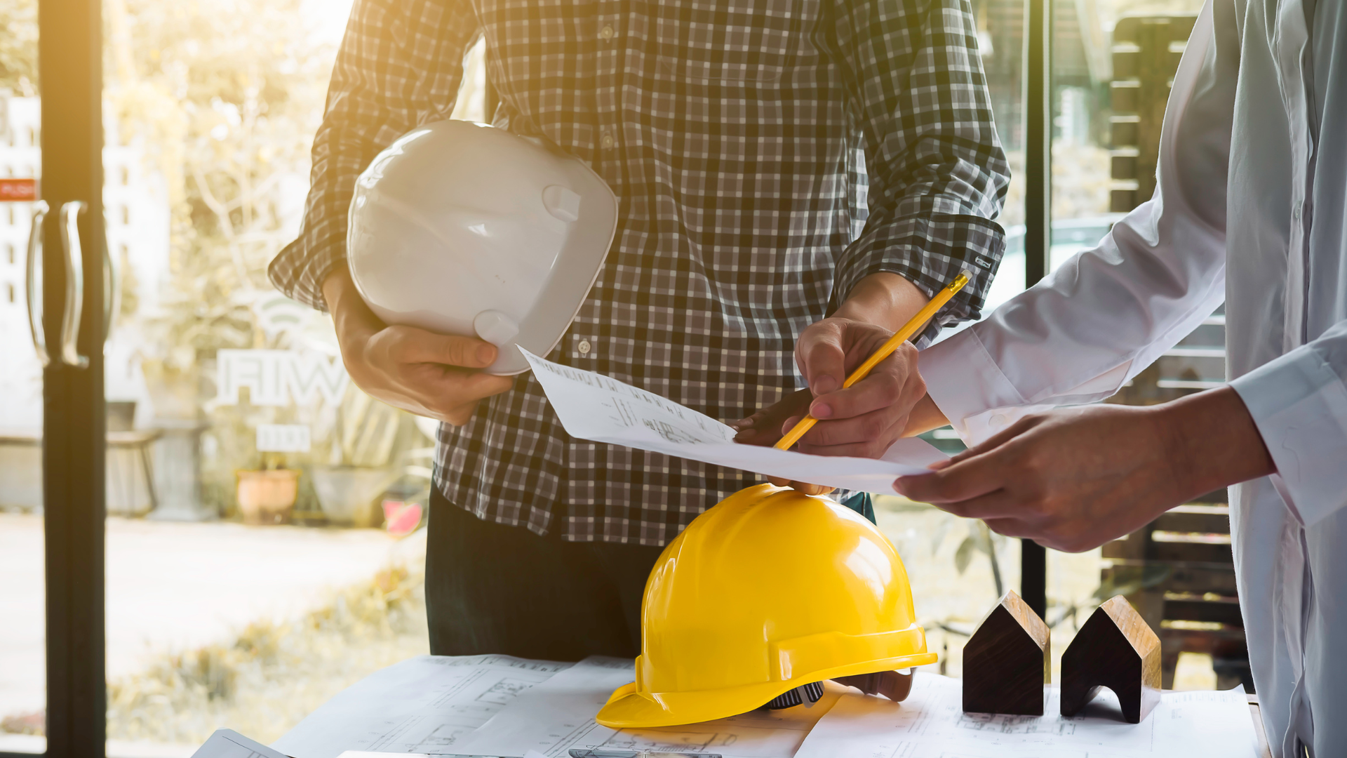 a group of construction workers are looking at a blueprint .