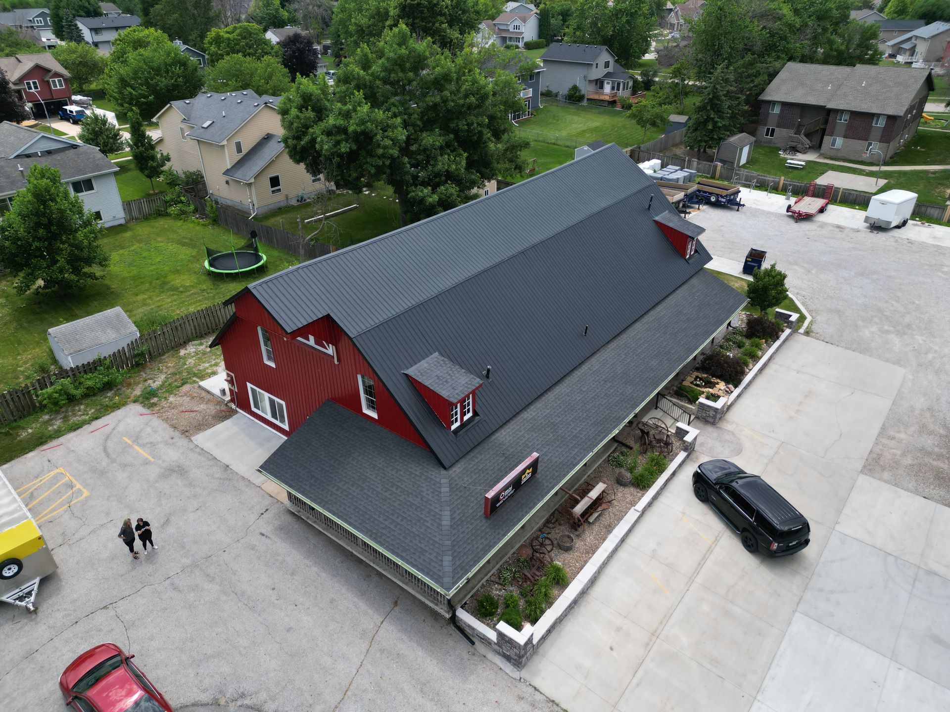 An aerial view of a red barn with a black roof