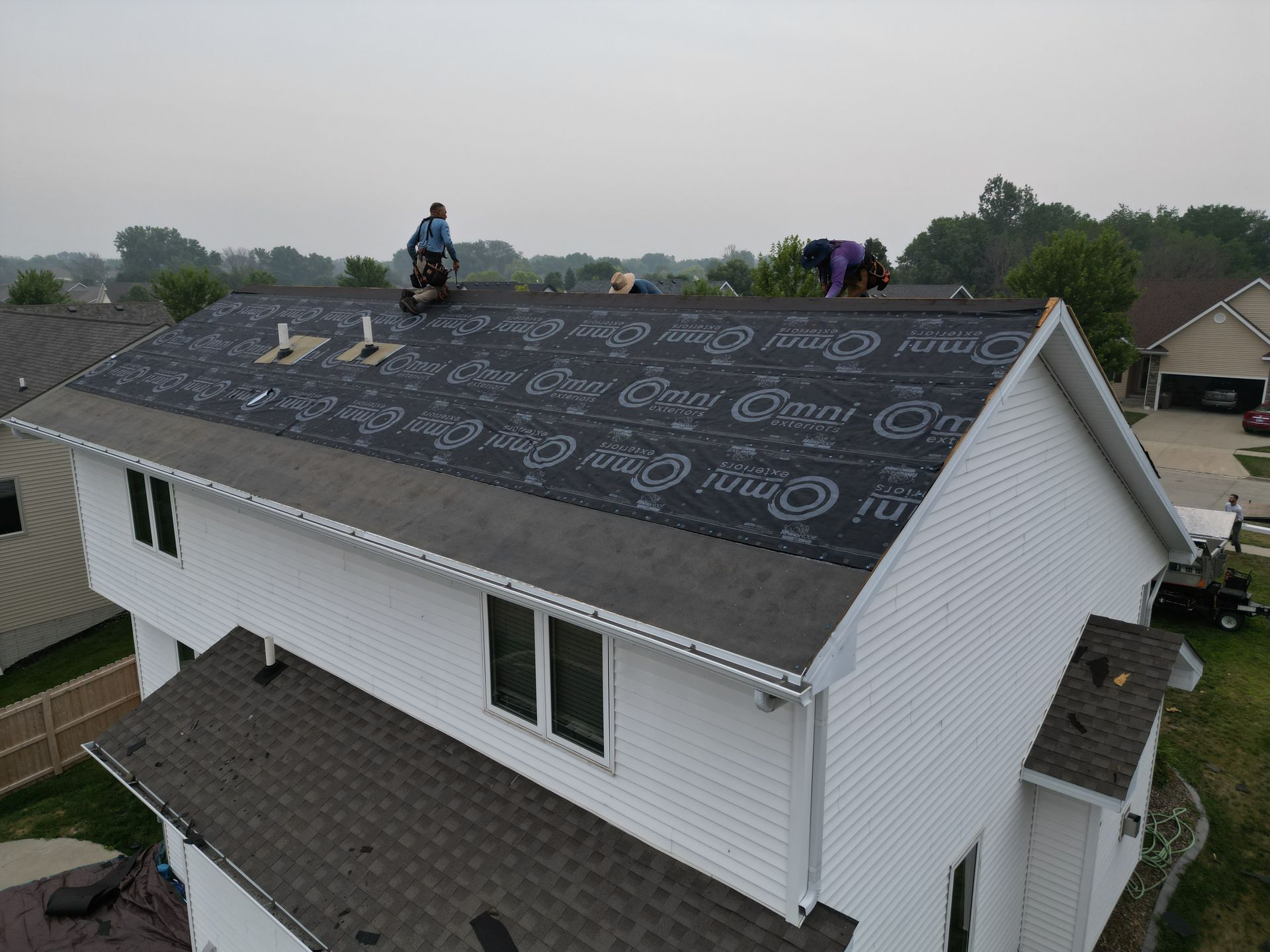 A white house with a black roof is being remodeled.
