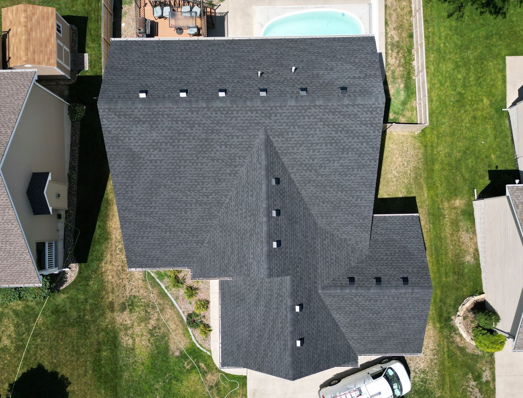 An aerial view of a house with a black roof and a pool.