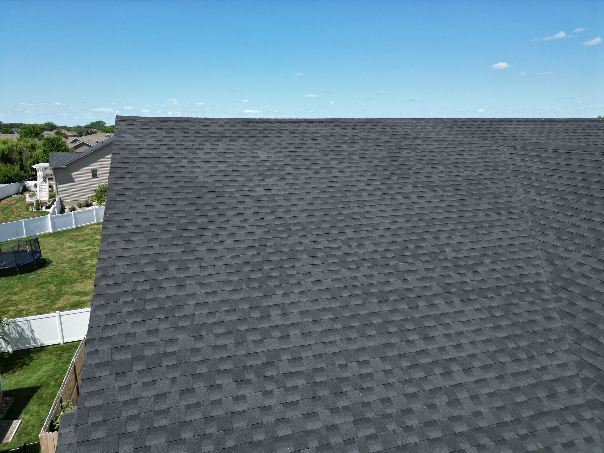 An aerial view of a house with a black roof and a white fence.
