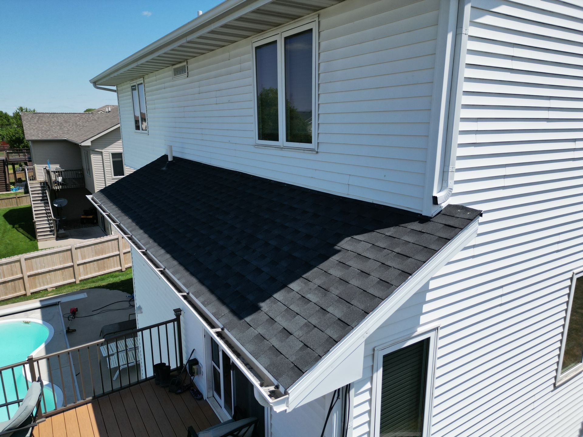 A white house with a black roof and a balcony.