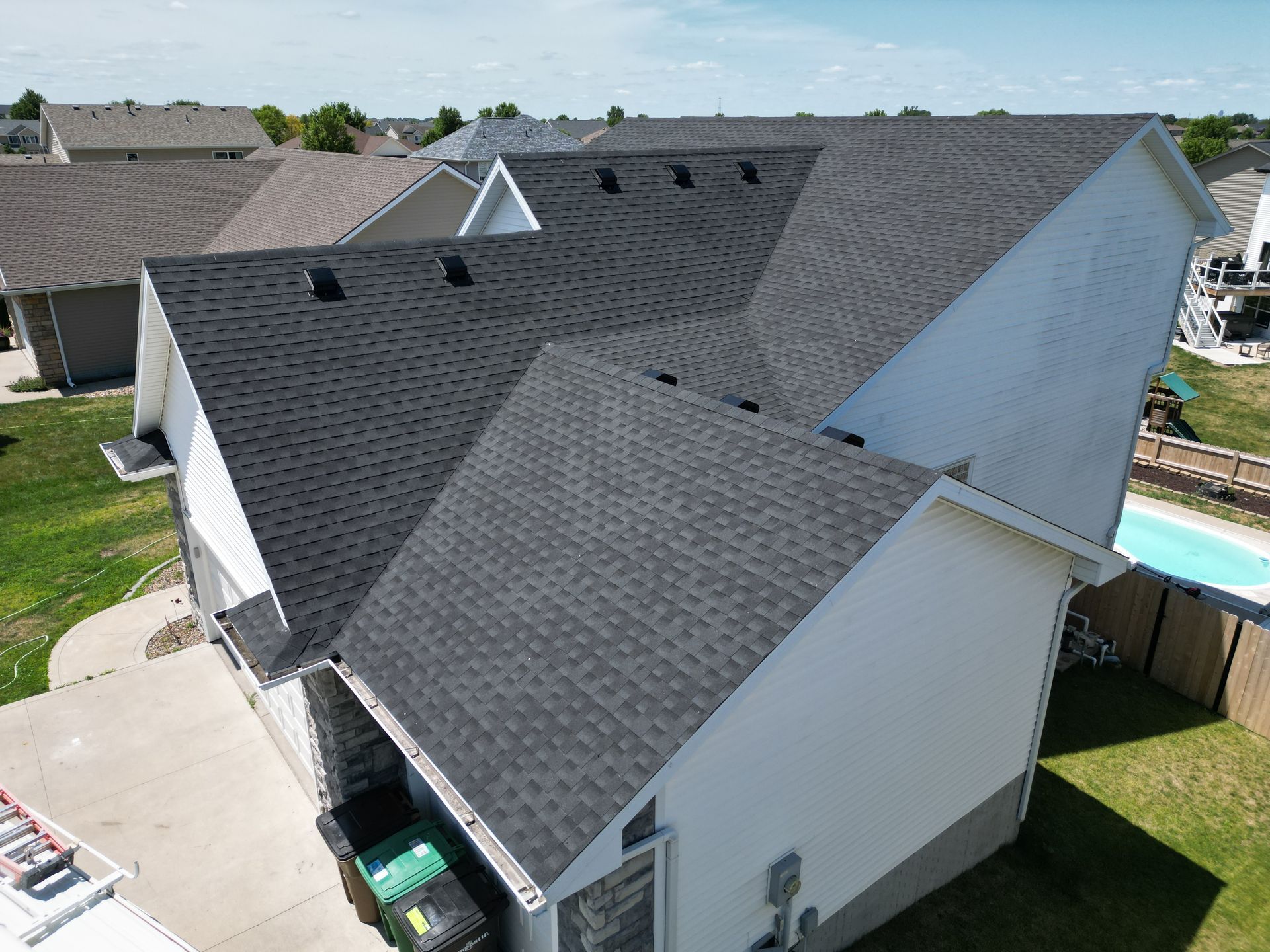 An aerial view of a house with a new roof and a pool.