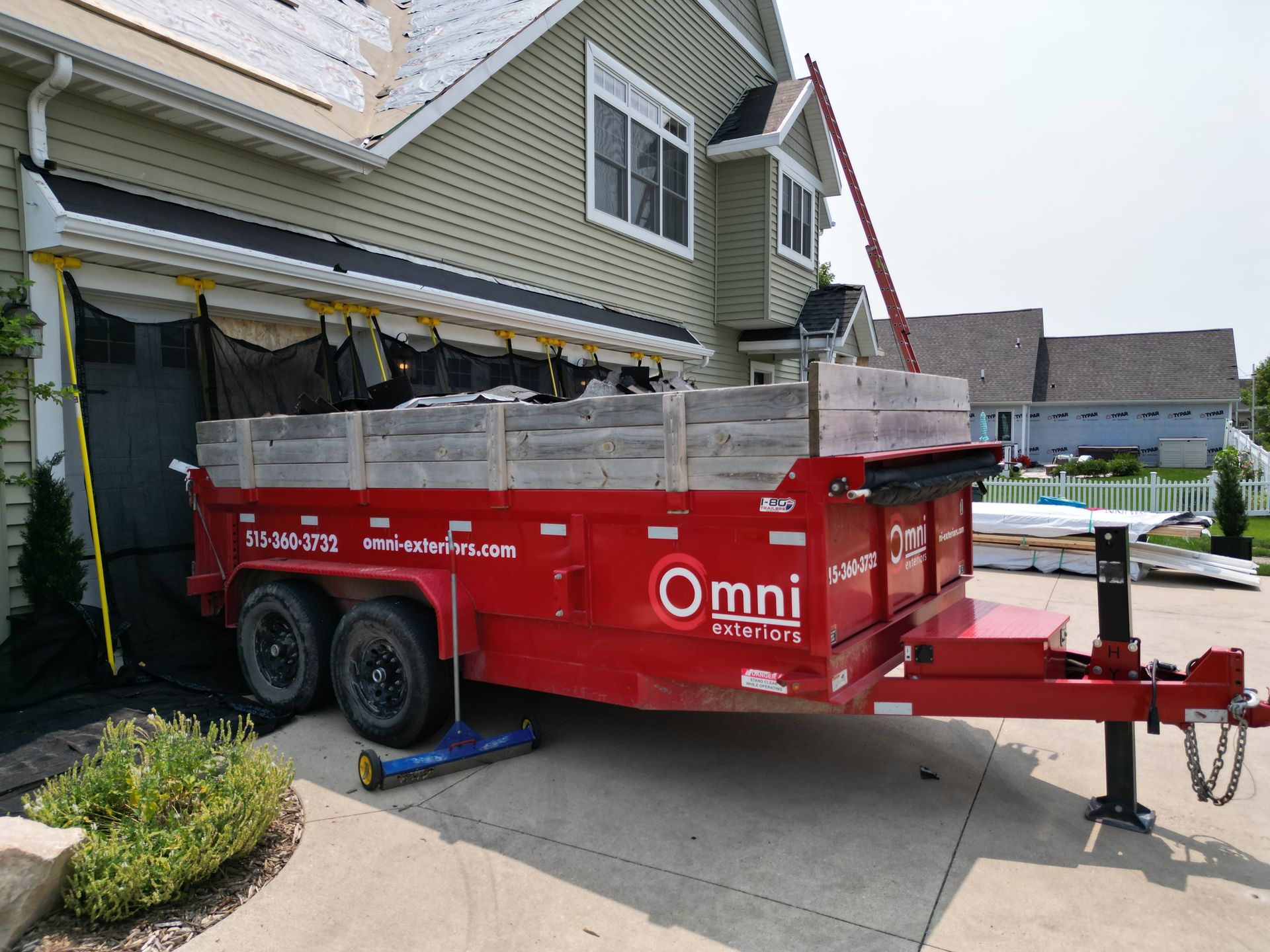 A red dumpster trailer is parked in front of a house.
