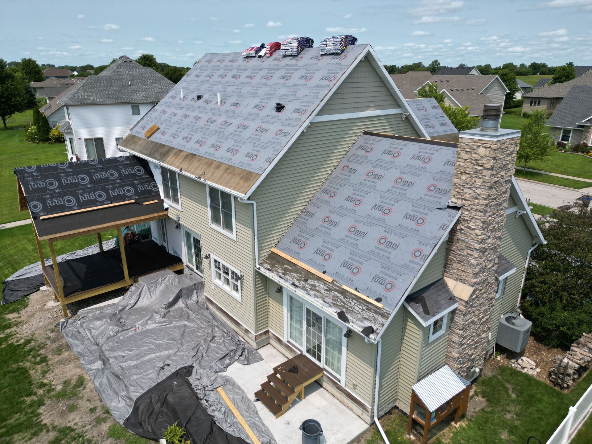 An aerial view of a house under construction with a roof being installed.