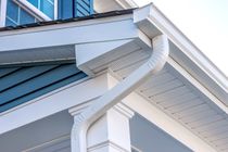 A close up of a white gutter on the side of a house.