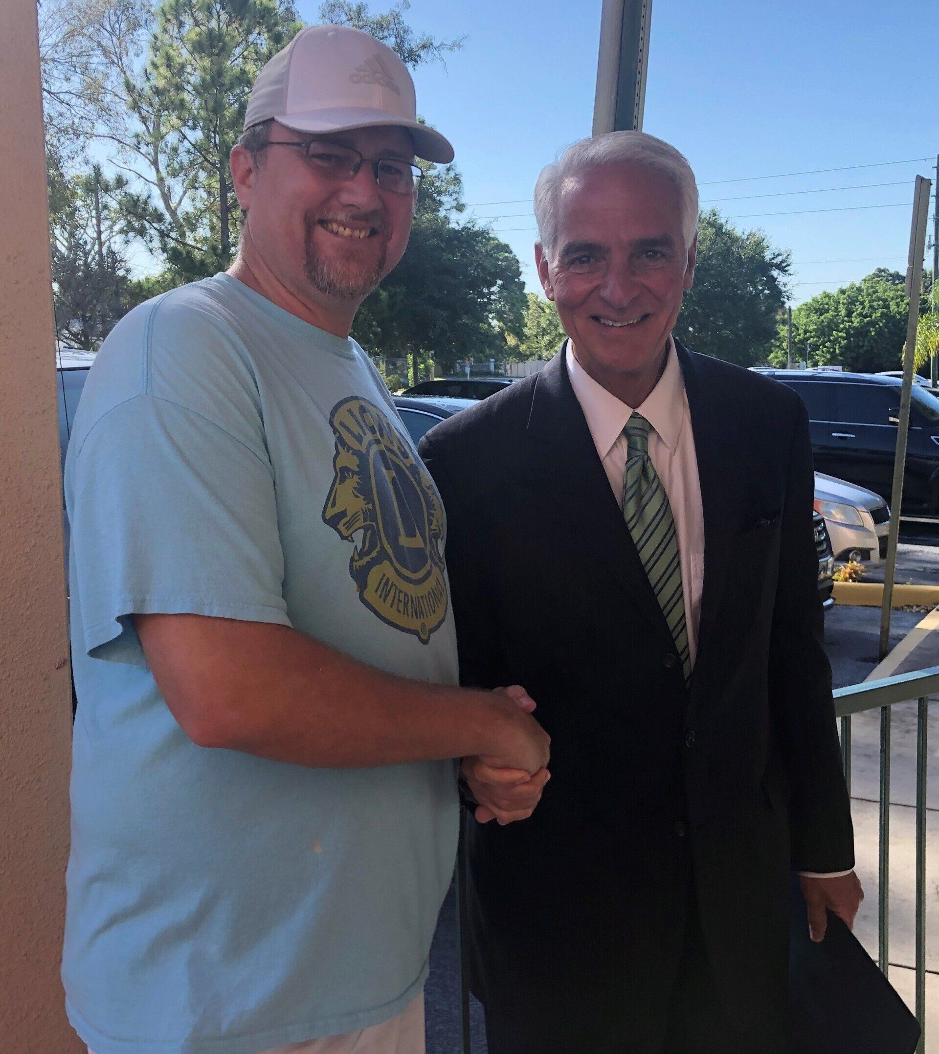 A man in a blue shirt is shaking hands with a man in a suit