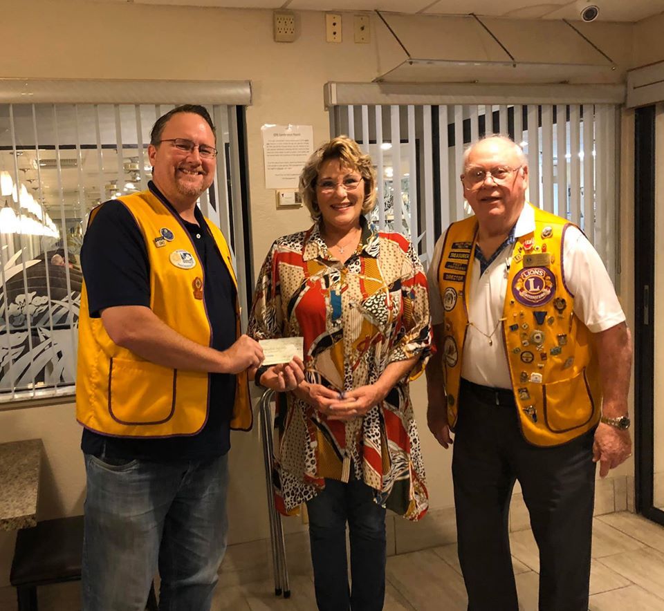 A man in a yellow vest is giving a woman a check