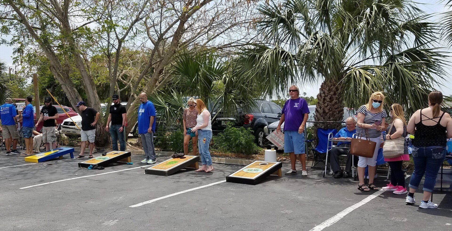 A group of people are playing cornhole in a parking lot.