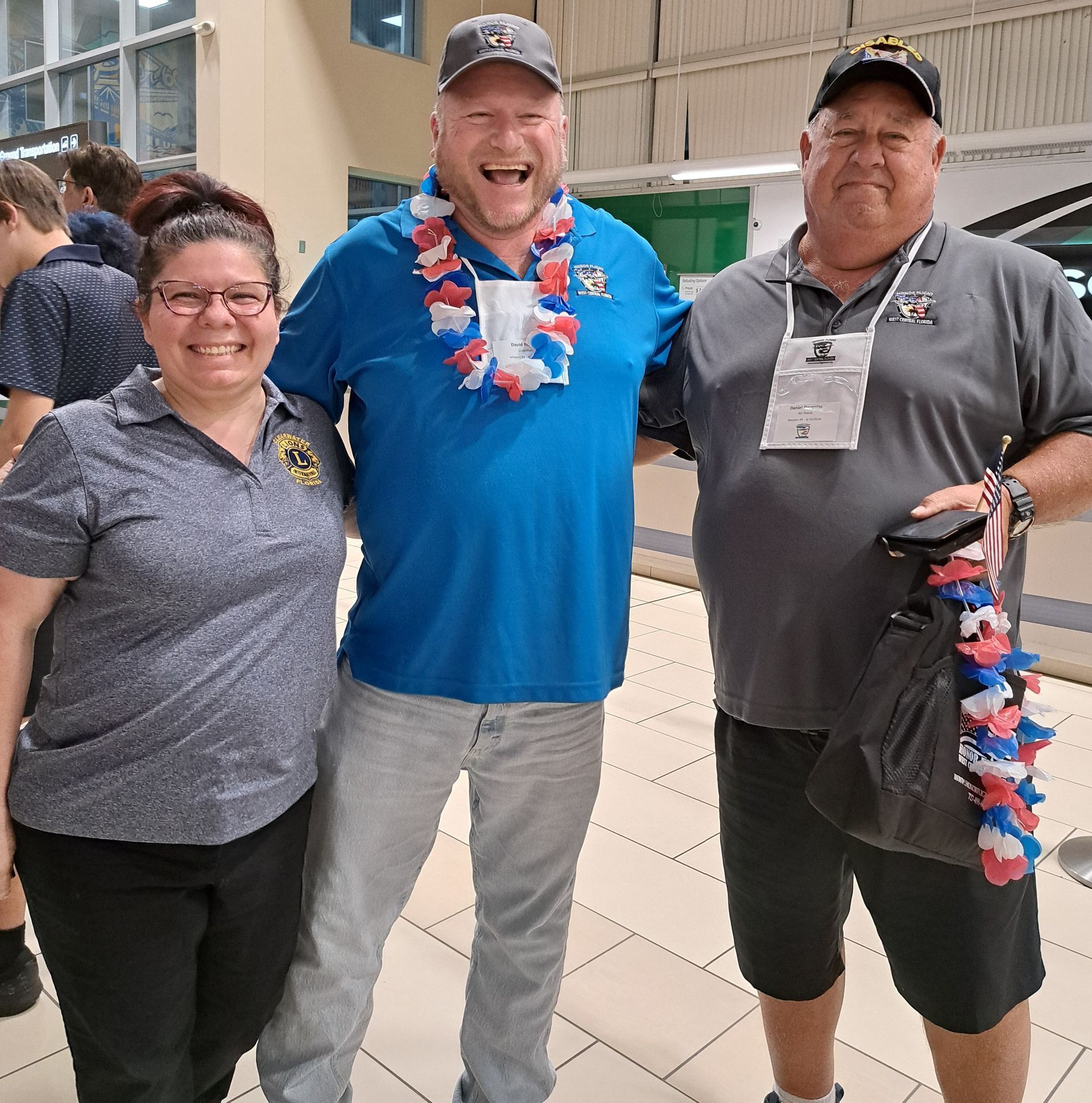 Three people posing for a picture with one wearing a lei