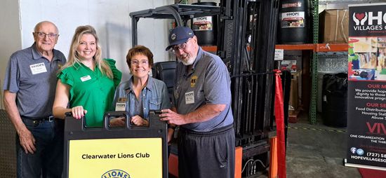 A group of people standing next to each other in a warehouse holding a sign.