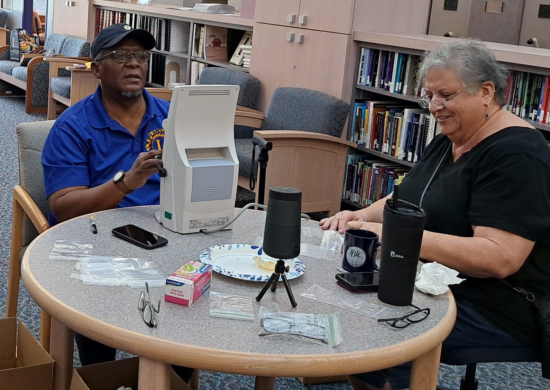 A man and a woman are sitting at a table in a library.