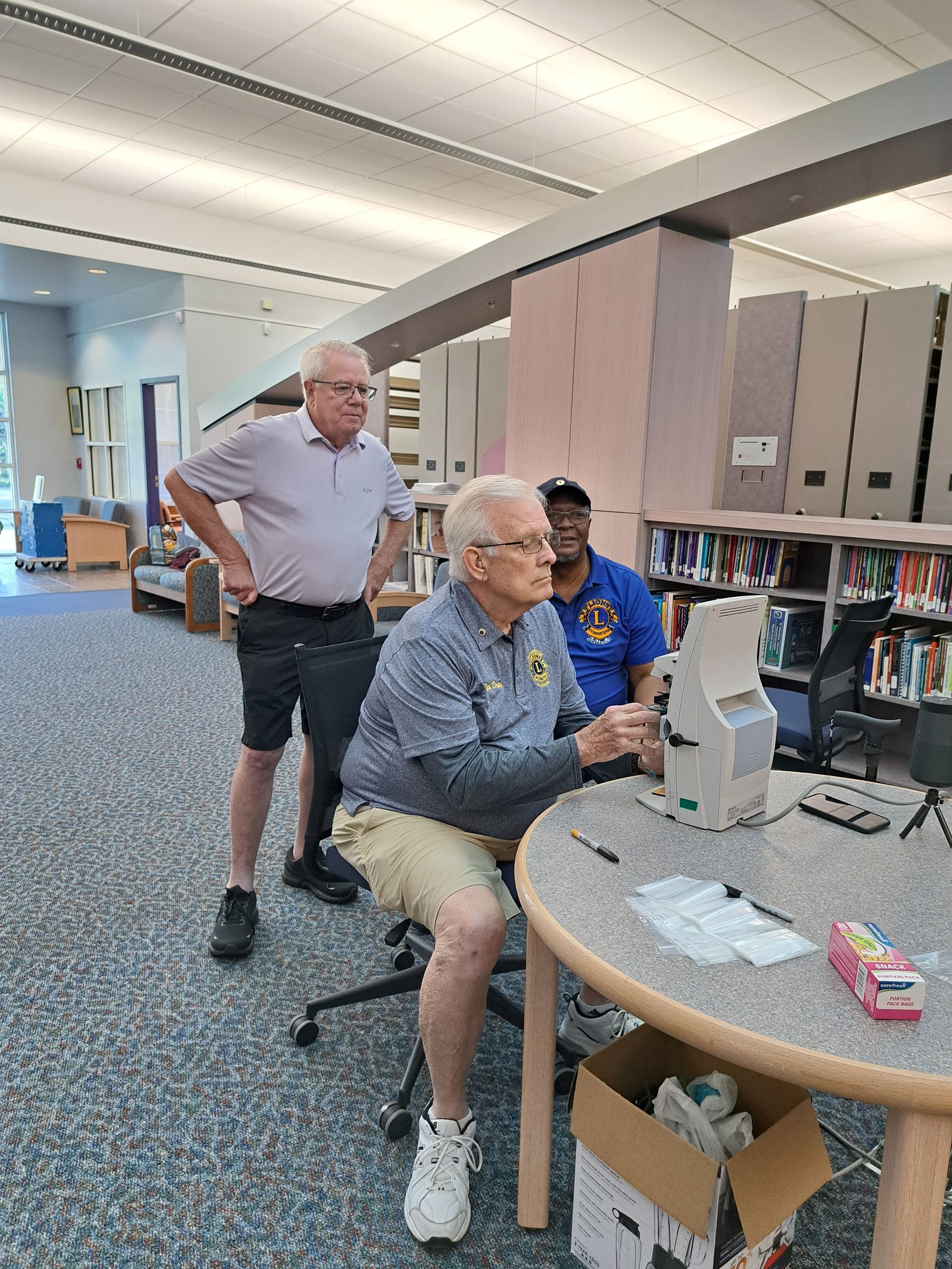A group of men are sitting at a table in a library.