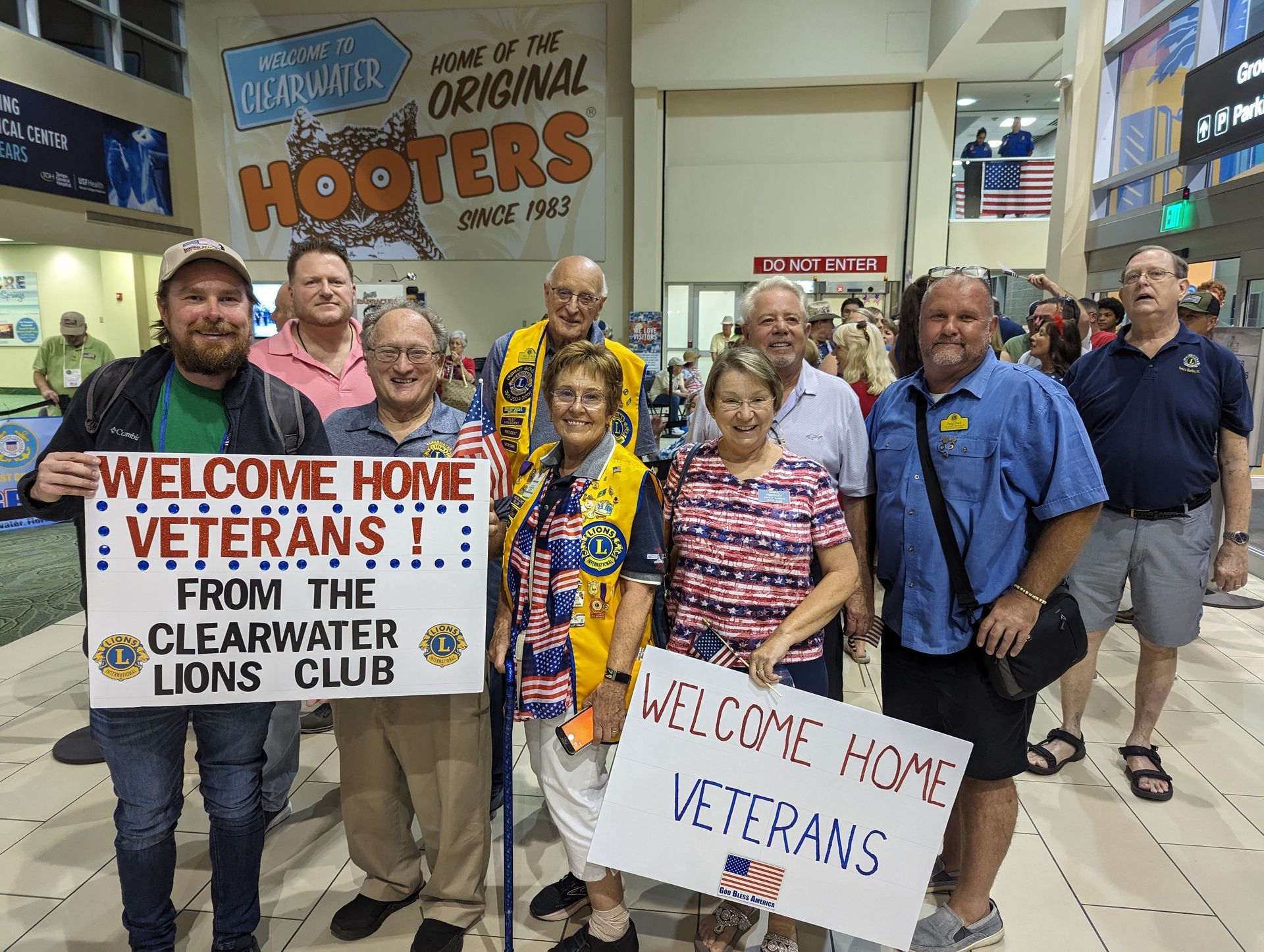 A group of people are holding signs that say welcome home veterans from the clearwater lions club.