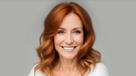 A woman with red hair is smiling and wearing a white shirt