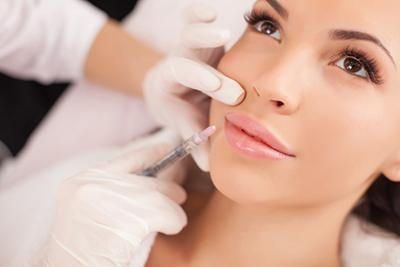 A woman is getting a botox injection in her lips.