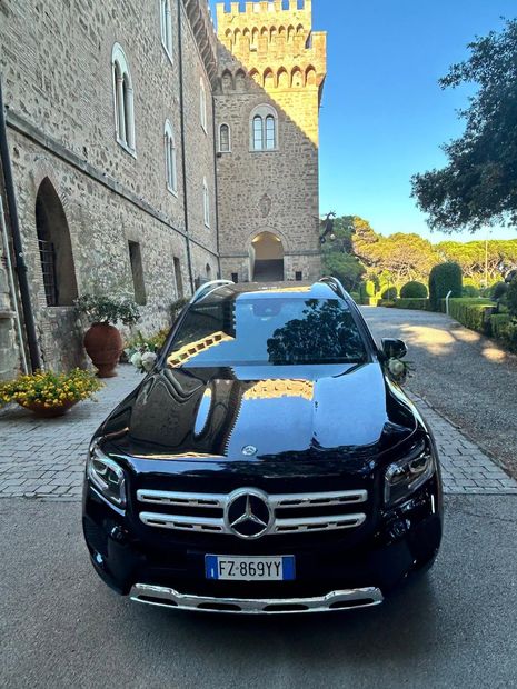 Berlina Mercedes nera davanti a una villa toscana con decorazioni floreali
