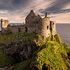 Antico castello di pietra su una verde scogliera a picco sul mare al tramonto