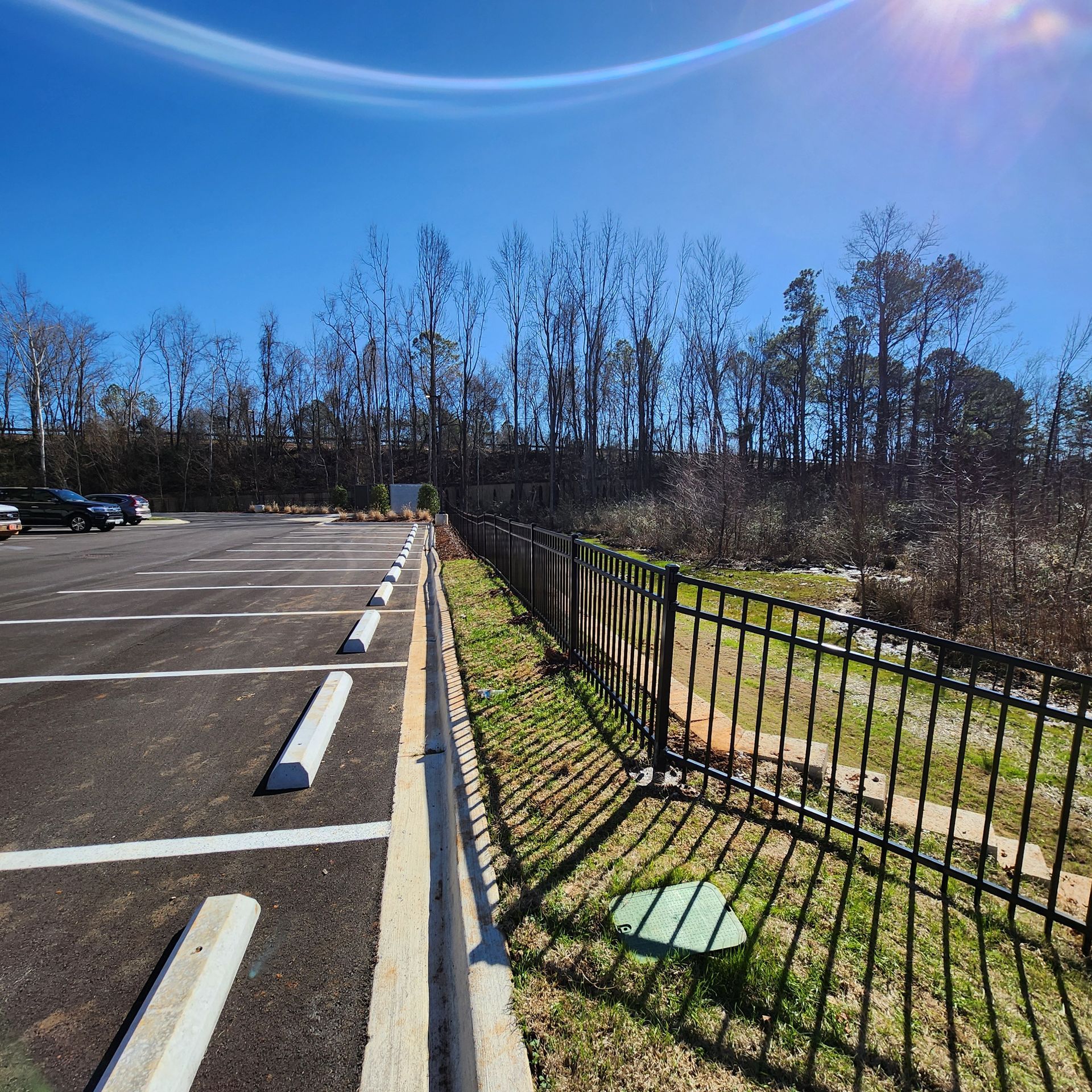 A parking lot with a fence and trees in the background