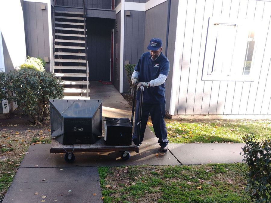 A man is pushing a cart with boxes on it in front of a building