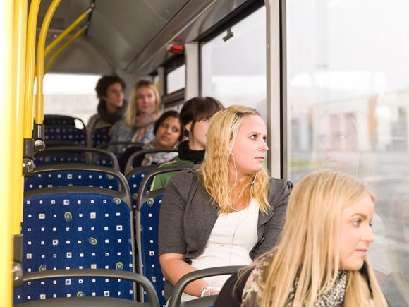 People seated on a bus, looking out the window. Blue seats, yellow railings.