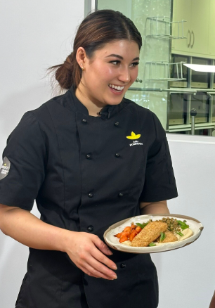 A woman in a chef 's hat is preparing food in a kitchen.