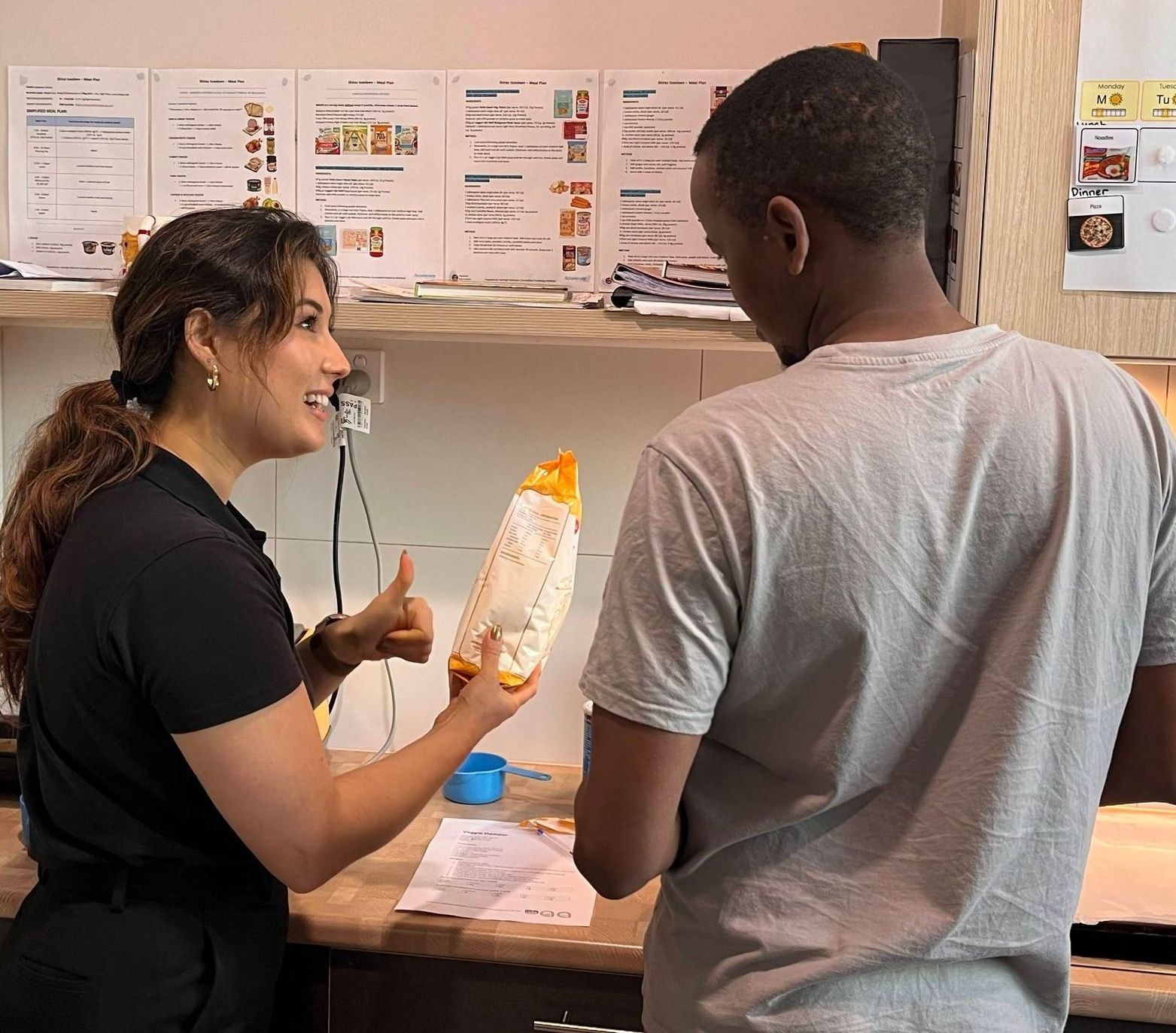 A man and a woman are talking in a kitchen
