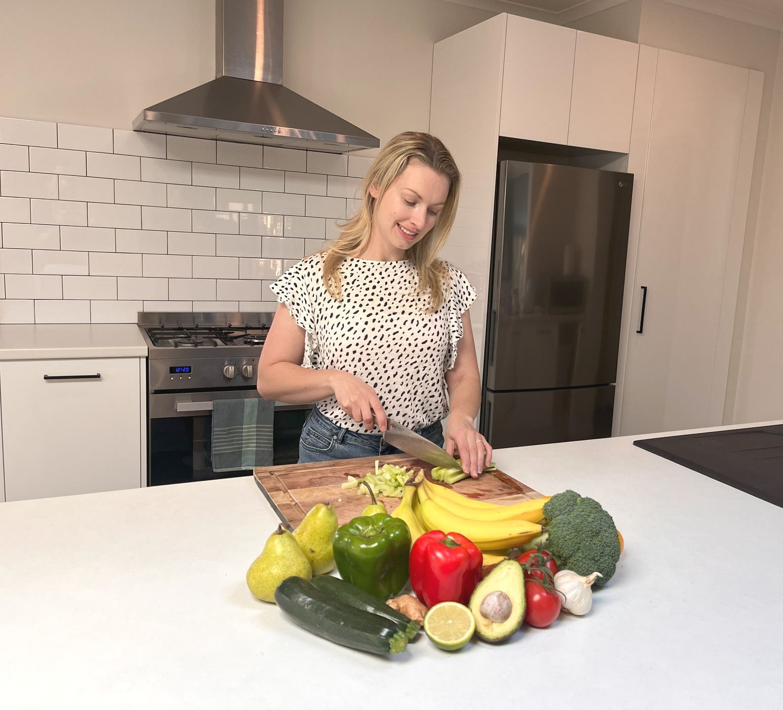 A woman is chopping vegetables in a kitchen